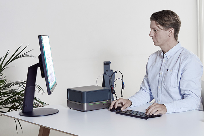Clinician sitting at desk with the Affinity Compact resting on the desk. The clinician is operating the Affinity Compact&rsquo;s HIT software module.